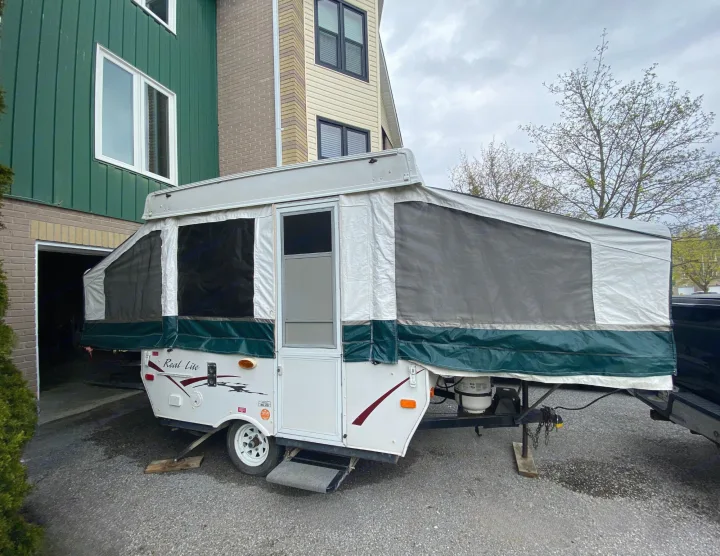 A white and green 'Real Lite' pop-up camper, extended and set up, sits in a driveway, ready for RV rental adventures.. Palomino Real - Lite 801 2007