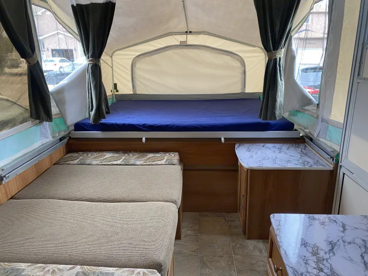 Inside a spacious pop-up camper, perfect for your next RV rental. Features comfy beds, seating, and marble counters.. Palomino Real - Lite 801 2007
