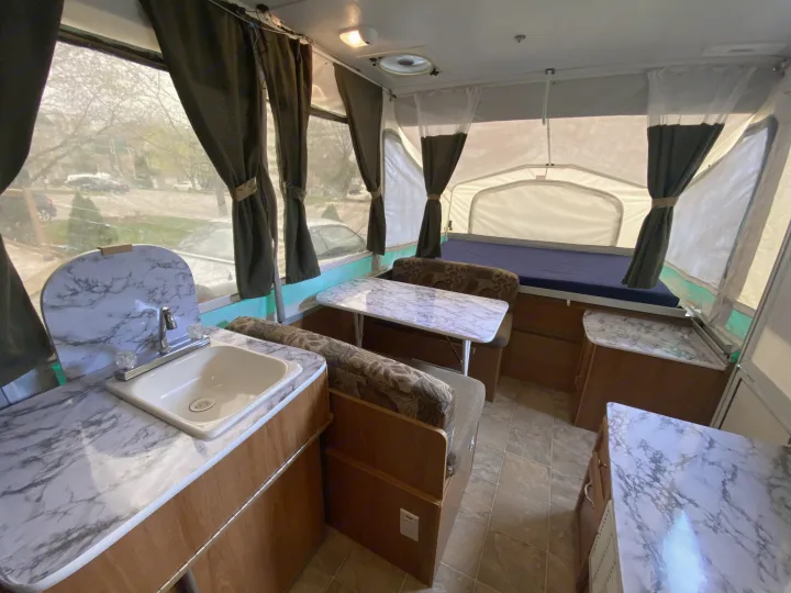 Bright RV rental interior: marble-look counters, sink, dinette, and bed. Enjoy compact living!. Palomino Real - Lite 801 2007