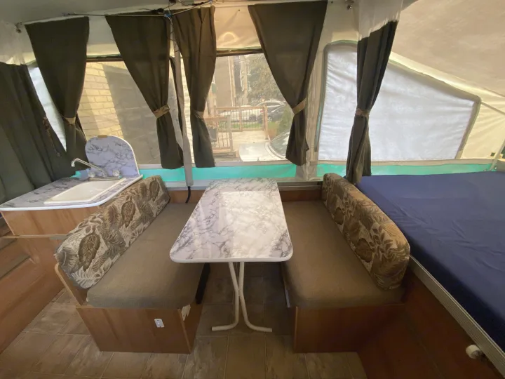 Compact RV rental interior featuring a cozy dinette, kitchenette with sink, and a comfortable bed. Ideal for travelers.. Palomino Real - Lite 801 2007