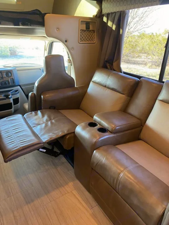 RV rental's inviting tan interior: comfortable recliners, one extended, with cup holders for relaxing travel.. Thor Quantum 2020