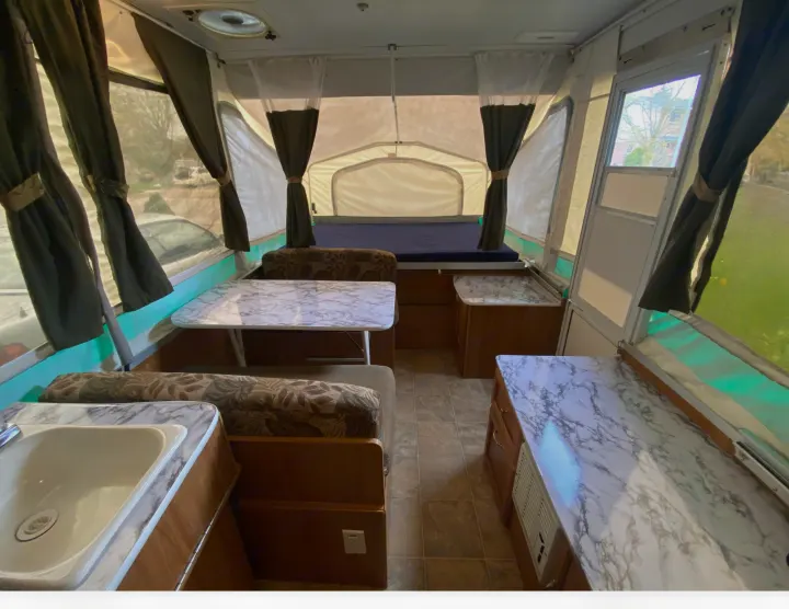 View inside an RV rental pop-up camper, featuring a dinette, sink, and rear bed area.. Palomino Real - Lite 801 2007