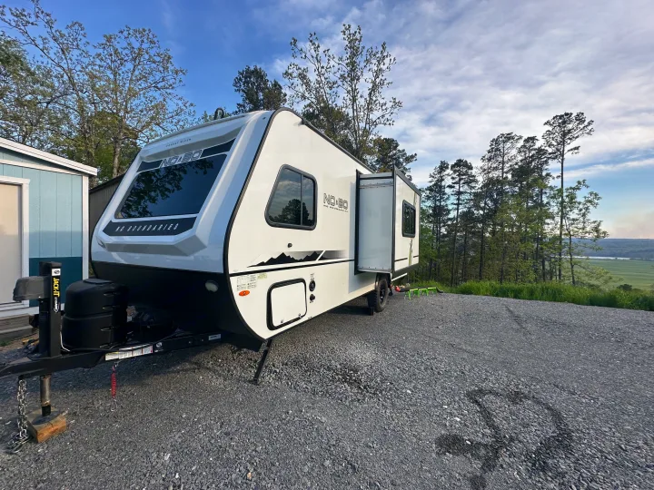 White No Boundaries rv rental trailer parked on gravel, slide-out extended, overlooking a scenic valley.. Forest River R-Pod 2020