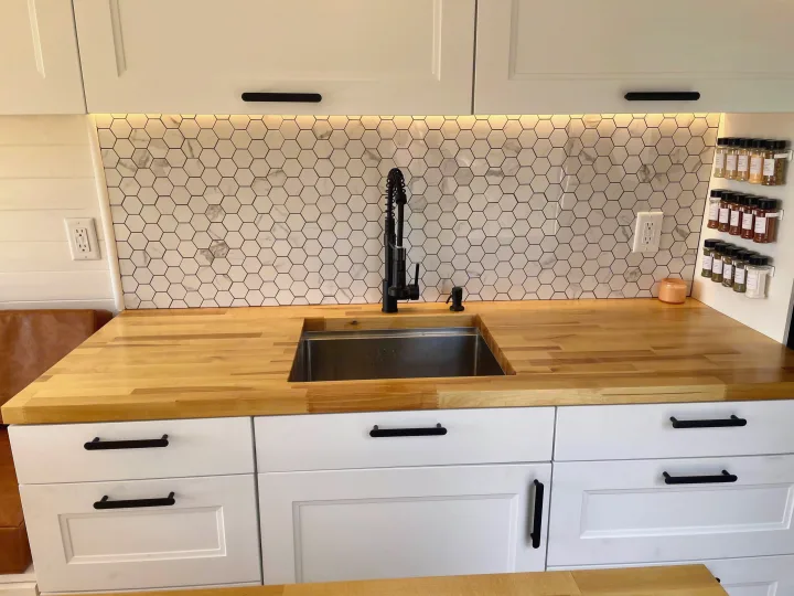 RV rental: Modern kitchen with white hex tile backsplash, butcher block countertops, black faucet, and under-cabinet lighting.. Dodge Ram ProMaster 2500 2021
