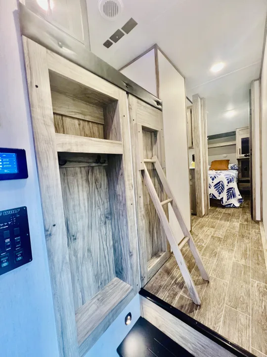 Explore this RV rental's clever bunk bed and wardrobe system, complete with ladder, maximizing space and comfort.. Forest River Cherokee Arctic Wolf 2021