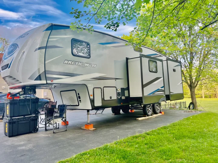 This modern Arctic Wolf fifth-wheel RV rental is fully set up on an asphalt driveway, ready for a comfortable stay.. Forest River Cherokee Arctic Wolf 2021