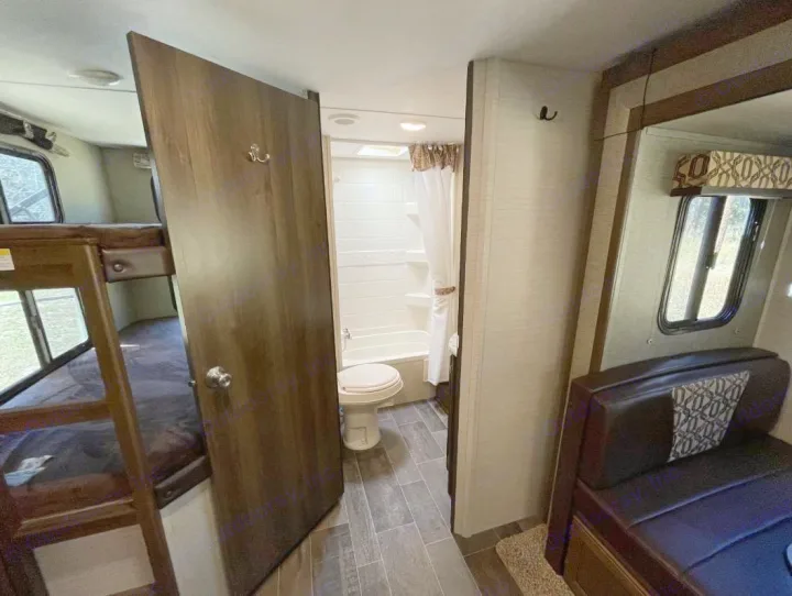 RV rental interior featuring bunk beds, a full bathroom with shower, and dinette seating in a compact layout.. Keystone Bullet Ultra 2018