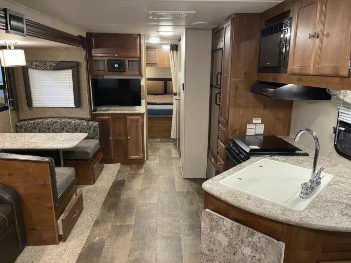 An RV rental interior with a kitchen, dinette, TV, and bunk beds, offering a compact and functional living space.. gulfstream Streamlite 2016
