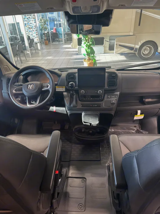 Inside a spacious RV rental van, featuring its Ram steering wheel, digital dashboard, and comfortable front seats.. Winnebago Solis 2023