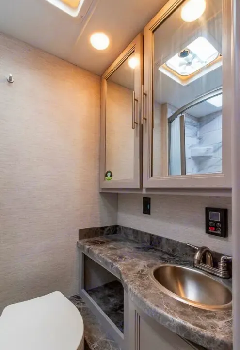 RV rental bathroom interior with a vanity, sink, toilet, and mirrored shower view.. Thor Outlaw 2024