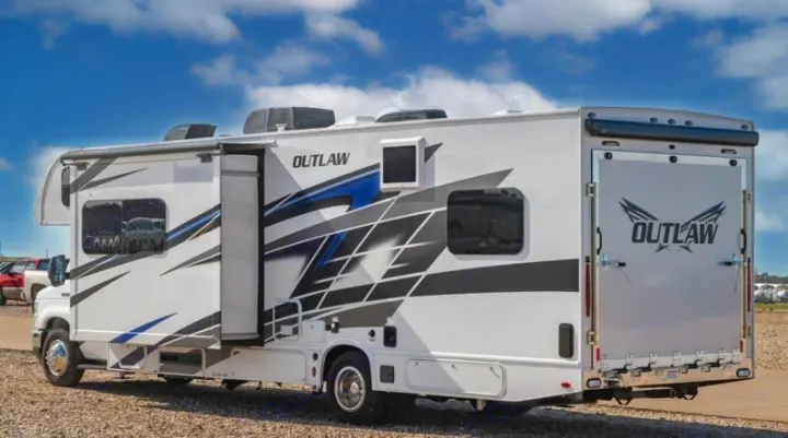 White Outlaw Class C toy hauler RV rental, showing side graphics and its rear ramp door for loading gear.. Thor Outlaw 2024