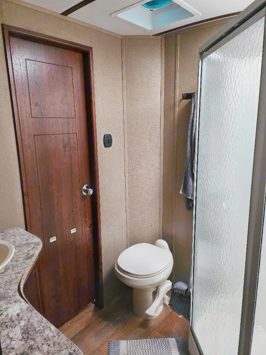 Functional and compact RV rental bathroom, featuring a toilet, shower stall, and partial view of the sink area.. Keystone Outback 2016