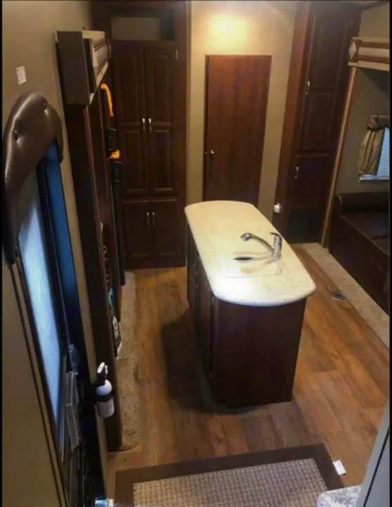 Spacious RV rental interior with kitchen island, wood floors, and ample storage, perfect for mobile living.. Keystone Outback 2016