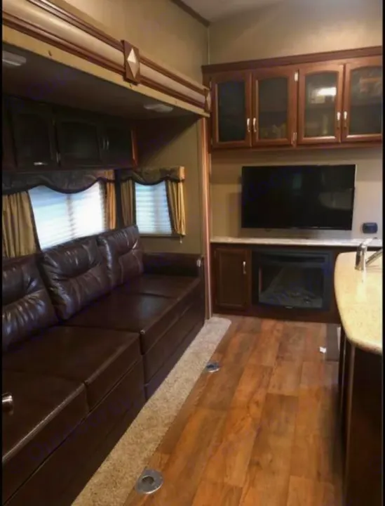 Experience comfort in this RV rental living area: plush leather sofa, entertainment center with TV & fireplace, and ample storage.. Keystone Outback 2016