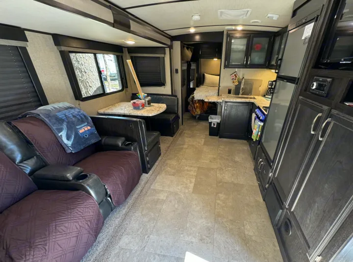 Step inside this cozy RV rental: living area with recliners, dining booth, full kitchen, and comfy bunk beds.. Grand Design Imagine 2019