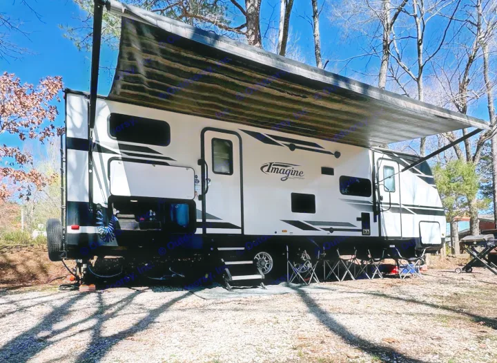 Sunny day, Imagine RV rental parked on gravel with extended awning & camping chairs.. Grand Design Imagine 2019