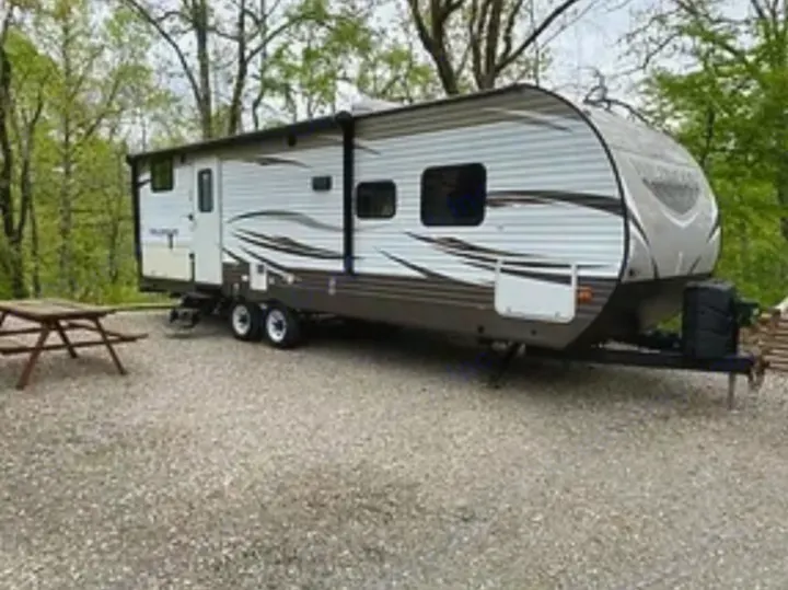 Spacious RV rental set up in a peaceful campground, complete with a picnic table for outdoor meals.. Forest River Wildwood 2018