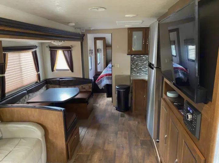 Spacious RV rental interior featuring a dinette, kitchenette, and a peek into the bedroom area.. Forest River Wildwood 2018