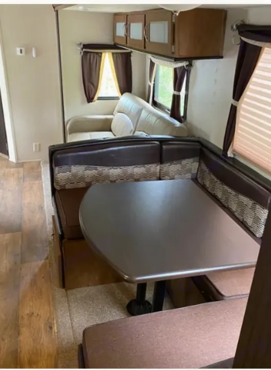 RV rental interior: U-shaped dinette with table, sofa, and overhead cabinets in the living area.. Forest River Wildwood 2018