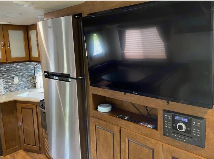 Modern RV rental interior showcasing a stainless steel kitchen and entertainment area with TV.. Forest River Wildwood 2018