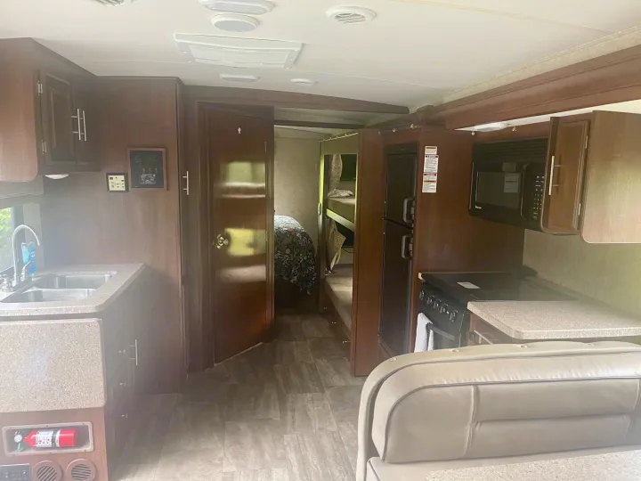 View of an RV rental's cozy interior, showing a kitchen, private bedroom, bunk beds, and living area. Ready for travel!. Georgetown GT3 2016