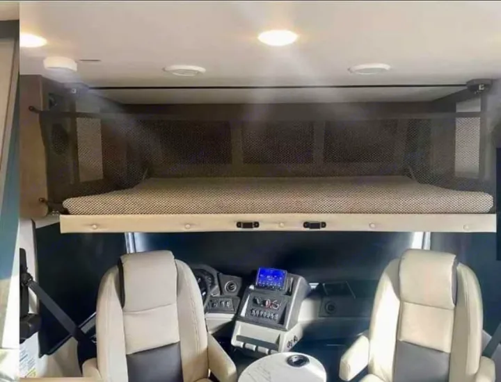 RV rental's front cab: a practical overhead bunk bed with safety netting is positioned above the driver and passenger seats.. FR3 FR3 Motorhome 2023