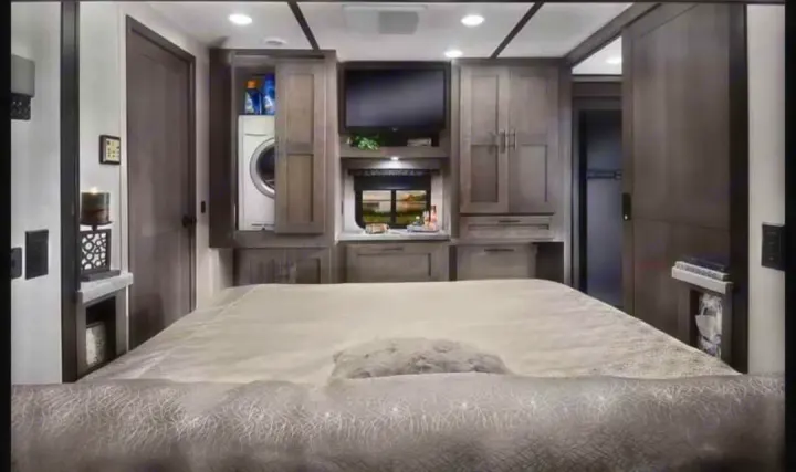 Spacious RV rental bedroom featuring a large bed, built-in storage, TV, and a convenient washer/dryer combo.. FR3 FR3 Motorhome 2023