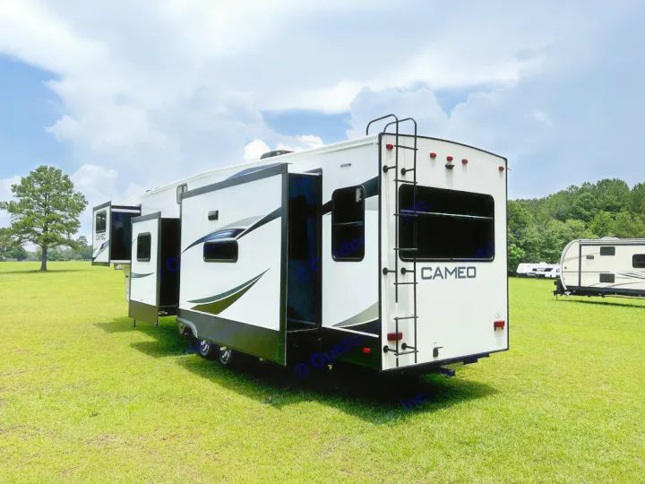 A large white Cameo fifth-wheel RV rental with extended slide-outs is parked in a sunny, green field, ready for travel.. Crossroads Cameo 2021