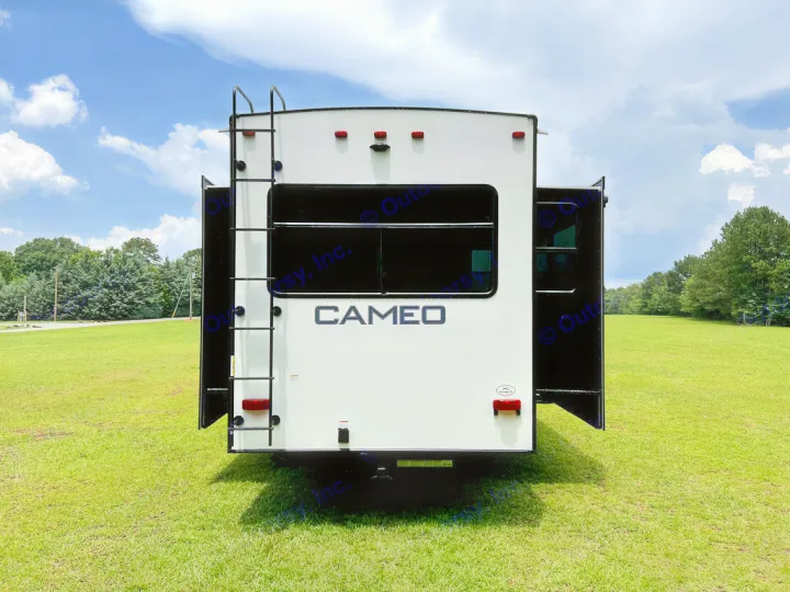 Rear view of a white RV with extended sections, parked on green grass under a blue sky. Consider this rv rental for travel!. Crossroads Cameo 2021