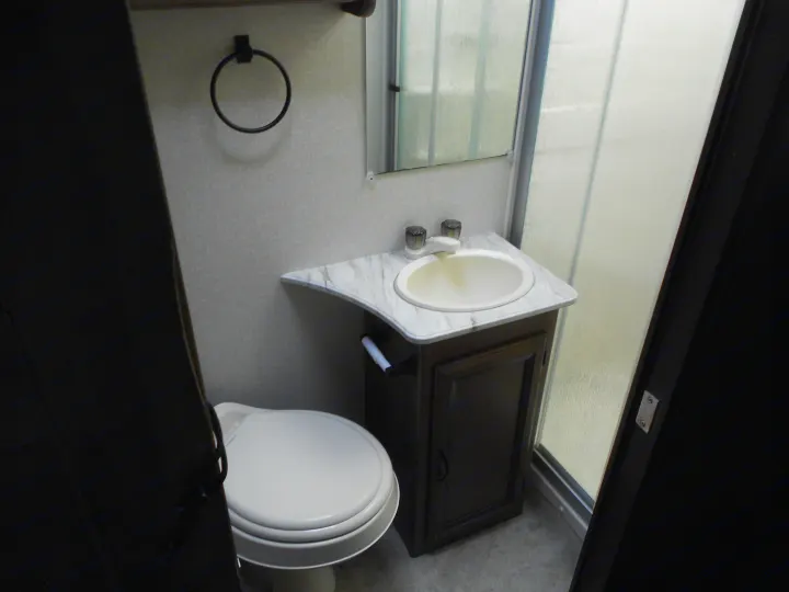 Inside an RV rental bathroom: toilet, vanity with sink & mirror, plus a compact shower. Functional space for travel.. Coachmen Freelander 2018