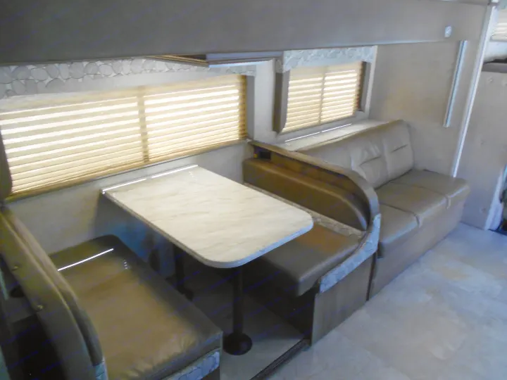 Spacious RV rental dinette with comfortable benches, table, and window blinds. Perfect for meals and travel comfort.. Coachmen Freelander 2018