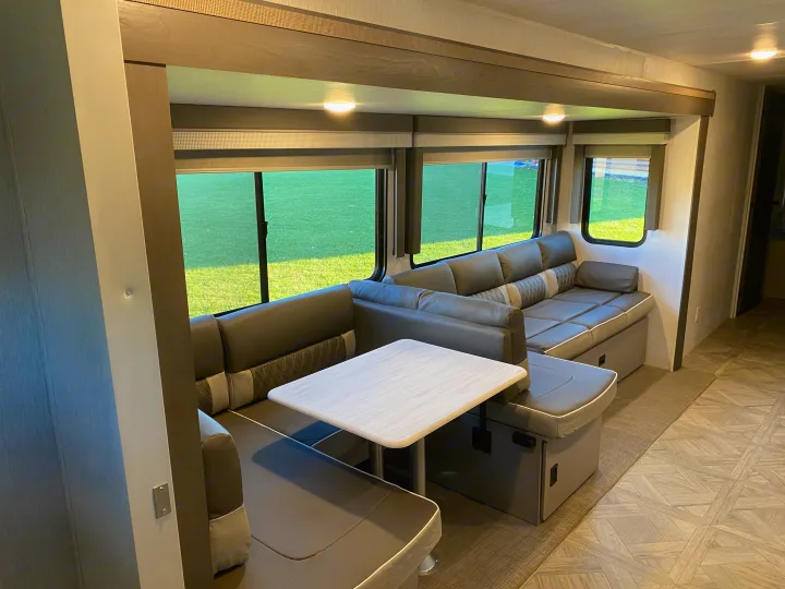 Spacious RV rental interior with comfortable U-shaped dinette, sofa, and large windows offering scenic views for travel.. Forest River Salem 2024