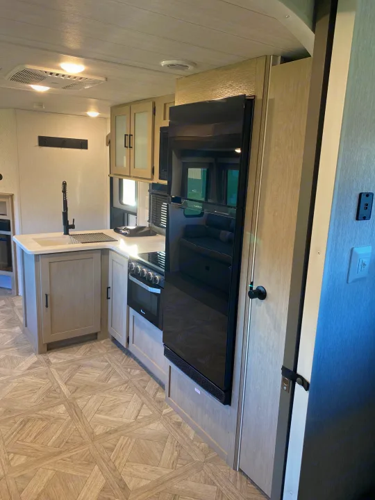 Explore this modern RV rental kitchen and living area, featuring sleek appliances, light wood, and a stylish interior.. Forest River Salem 2024
