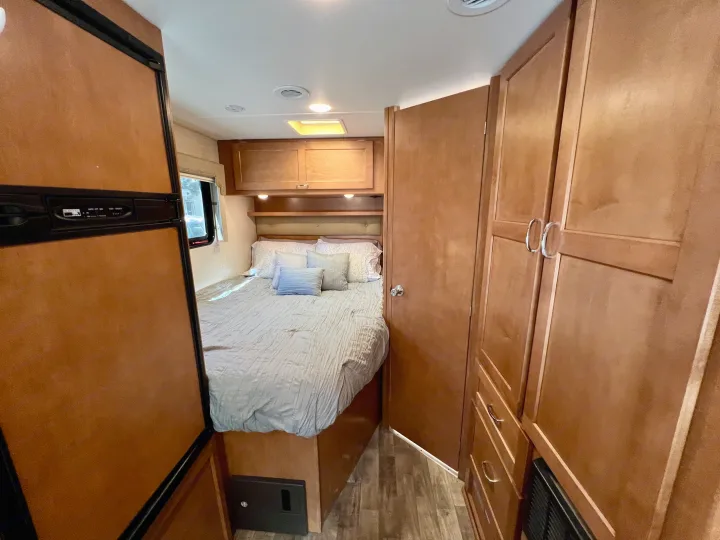 Inside this RV rental: a compact bedroom with a comfortable bed, storage, and small fridge.. Winnebago Minnie Winnie 2017