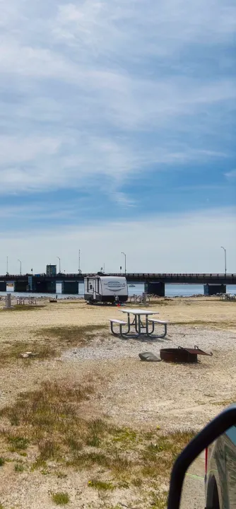 RV rental parked at a waterfront campsite. Features a travel trailer, a bridge, picnic table, and fire pit.. Keystone RV Springdale Mini 1800BH 2024