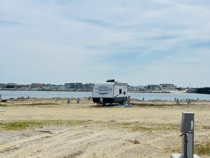 Springdale RV rental parked at a waterfront campsite with houses across the bay. Ideal for a relaxing travel trailer getaway.. Keystone RV Springdale Mini 1800BH 2024