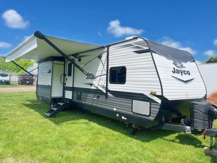 White & black Jayco travel trailer with extended awning on grass, ready for your RV rental.. Jayco Jay Flight 2022