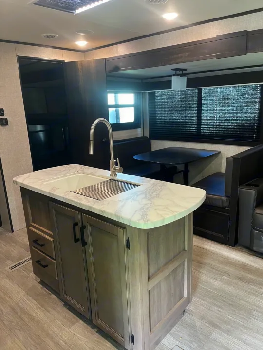 Inside this RV rental: a bright kitchen island with a sink, a cozy dining booth, and living space for comfortable trips.. Jayco Jay Flight 2022
