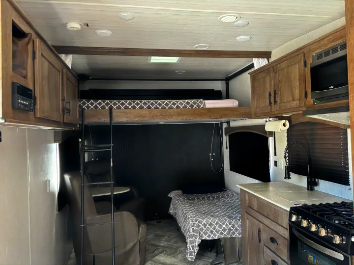 Modern RV rental toy hauler interior, featuring kitchen, bunk beds, and recliners.. Forest River Stealth 2022