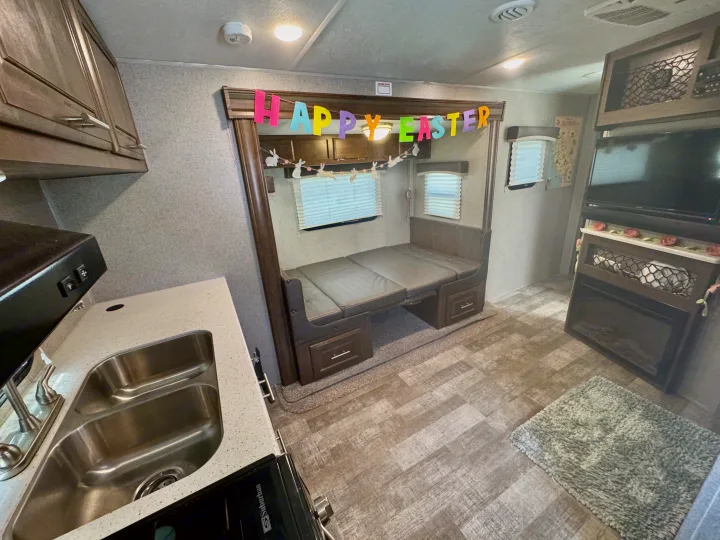 Cozy RV rental interior shows kitchen, convertible sofa bed, entertainment center, and festive Easter decor.. Forest River Rockwood Mini Lite 2020