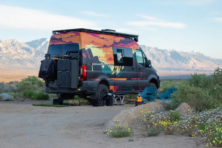 Colorful custom RV rental parked for camping with mountain views, campfire, and chairs. Perfect for outdoor adventures.. Mercedes-Benz Sprinter 2023