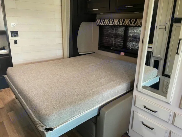 Inside an RV rental: a modern murphy bed extended, offering a cozy sleeping area within the compact living space.. Entegra Coach Odyssey 2021