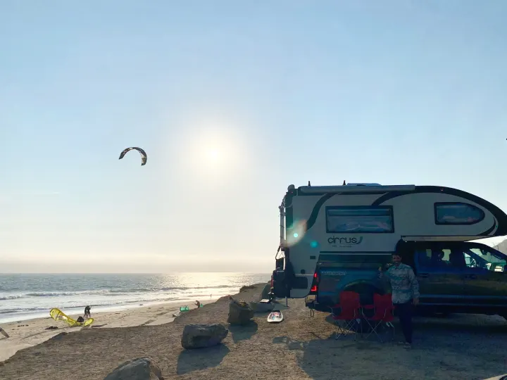 Enjoy a scenic rv rental experience! A nuCamp Cirrus truck camper parked on a sandy beach at sunset, with kitesurfers.. Ford F350 Diesel Double Cab 2020