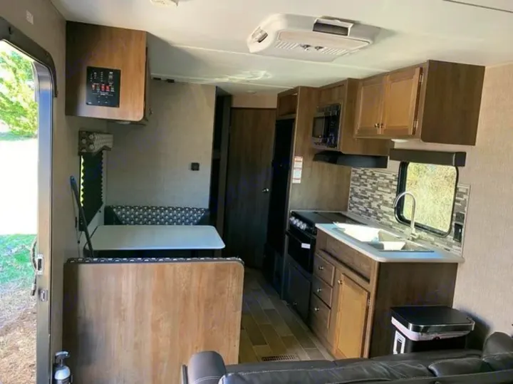 Inside this RV rental: a compact yet functional kitchen, dinette, and living area. Enjoy your travels.. Dutchmen Coleman 420LH 2020