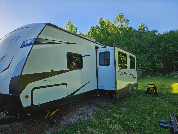 RV rental with slide-out extended, parked in a grassy setting with a yellow generator nearby.. Keystone RV Bullet Ultra Lite 2022