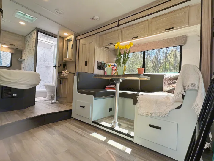 Modern RV rental interior: dinette, kitchen, bed, & bath. Bright & spacious camper living.. Forest River Sunseeker LE 2023