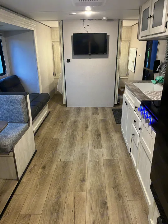 Clean RV rental interior: modern kitchen, cozy dinette, and light wood-look flooring lead to private sleeping areas.. Shasta RVs I5 526DB 2024