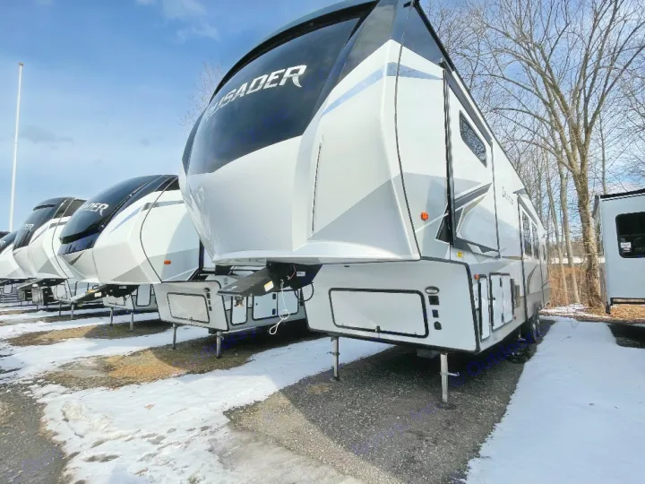 Rows of white and black fifth-wheel RVs, like Crusader models, lined on a snowy outdoor lot, perfect for an rv rental adventure.. Crusader Crusader Fifth Wheel 2022
