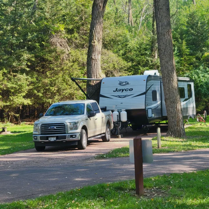 Ford pickup with Jayco RV rental at a scenic, wooded campsite, ready for your outdoor adventure.. Jayco Jay Flight 2021