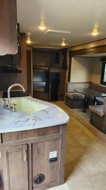 RV rental interior: kitchen with marble-look counter, dinette, and bunk beds visible, ideal for your next adventure.. Jayco Jay Flight 2021